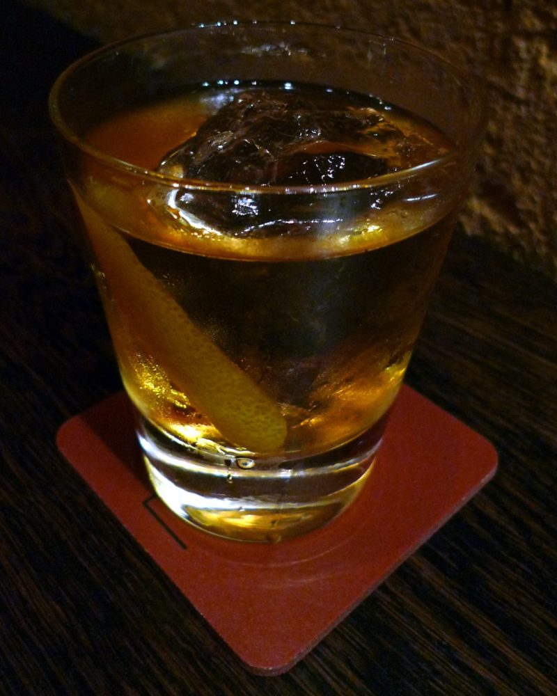 Low Ember — A whiskey sour built under a smoking cloche — the glass fills with cedar smoke before the first sip ever reaches it.